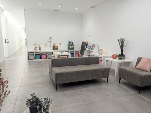 Sala de espera de Presencia Dental en Massamagrell con sofás y zona infantil con juguetes y pizarra