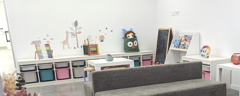 Zona infantil en la sala de espera de Presencia Dental con libros, pizarra, ábaco y mesa baja